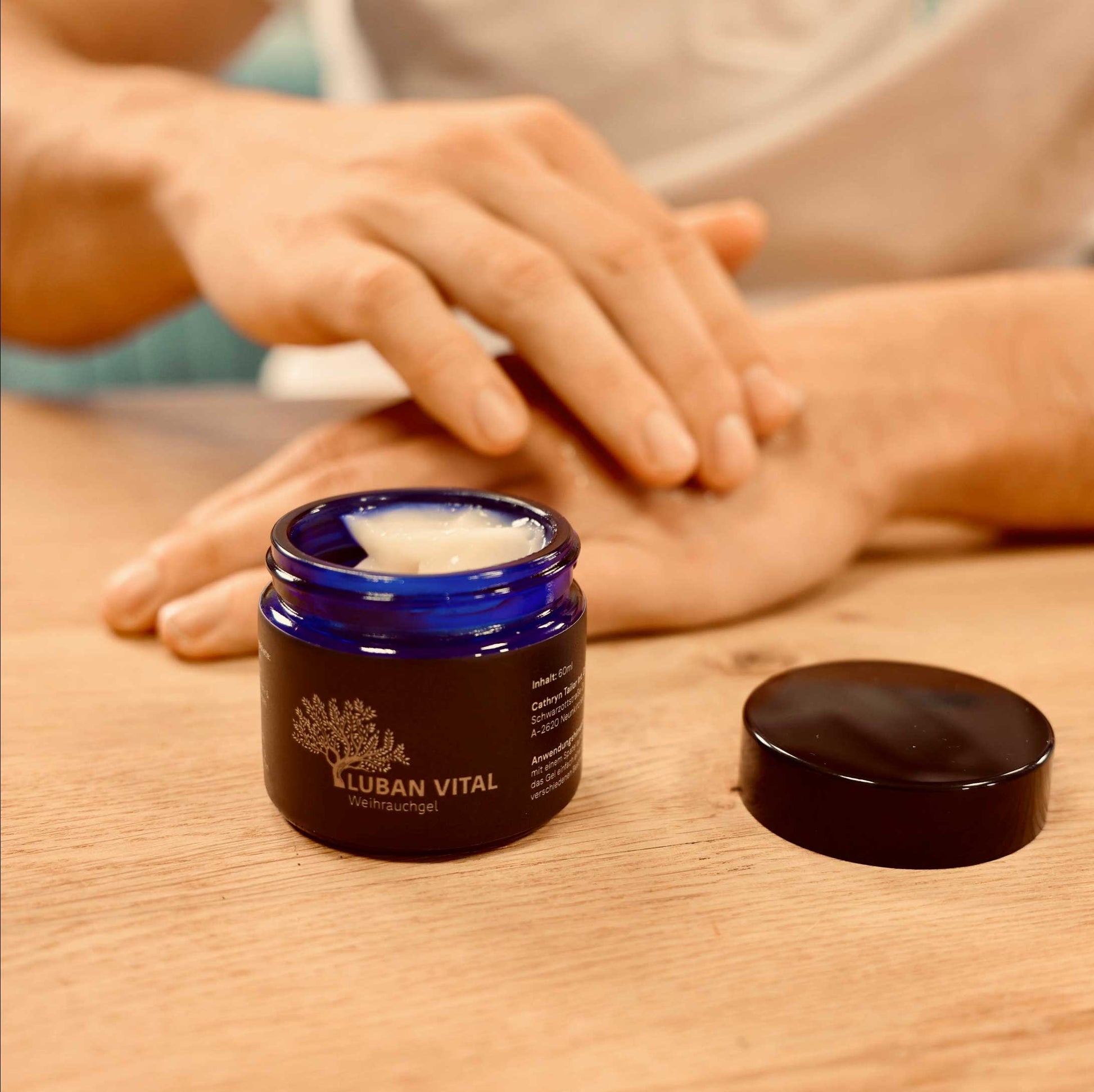 Hand entnimmt Creme aus einem blauen Glas-Tiegel Luban Vital Weihrauchgel